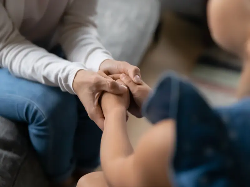 adult holding young girl's hands while providing pastoral and spiritual care