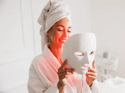 A woman with a red light therapy mask trying to have healthier skin