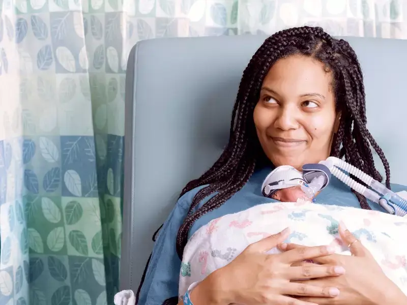 Helen Woldemichael, mother, sitting in the NICU unit holding her premature newborn, Amari, for skin-to-skin contact