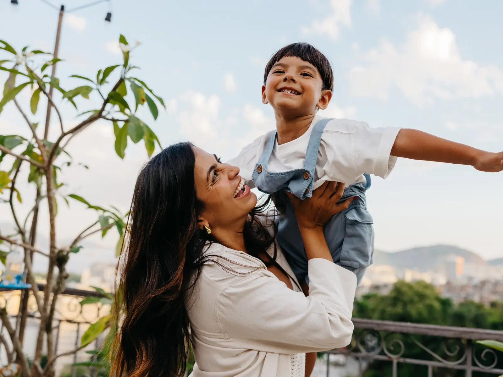 Need to boost your immune system? A healthy woman holds her son in the air as they navigate flu season with healthy eating, exercise and the flu vaccine.