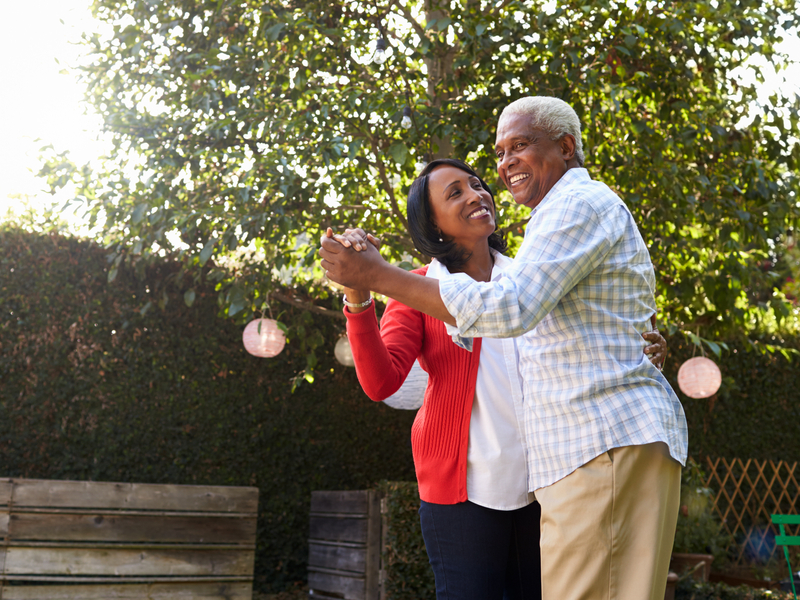 Senior couple dancing in their back garden