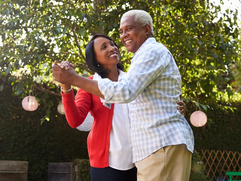 Senior couple living with joint pain, dancing in their backyard
