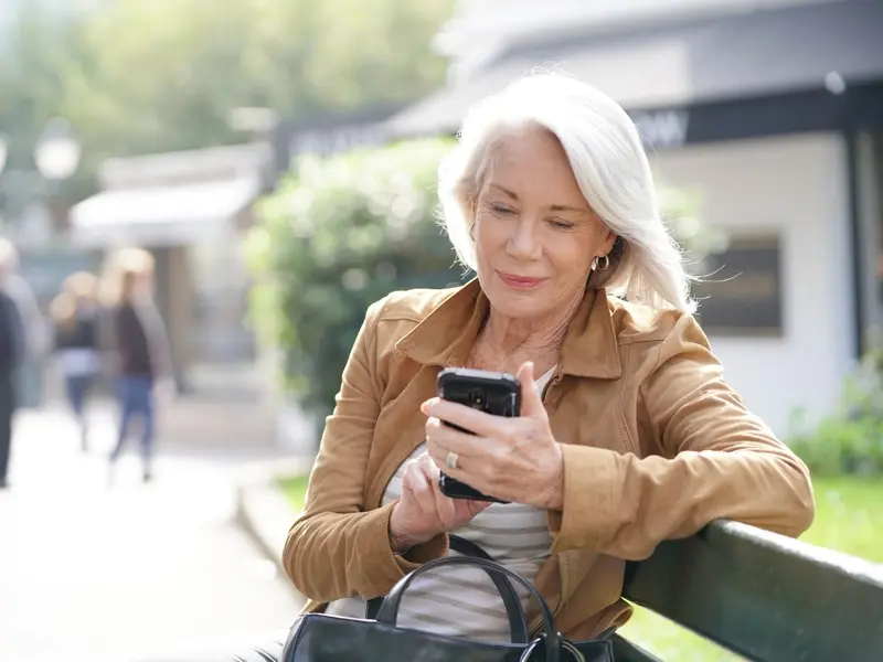 Beautiful senior woman texting outdoors 