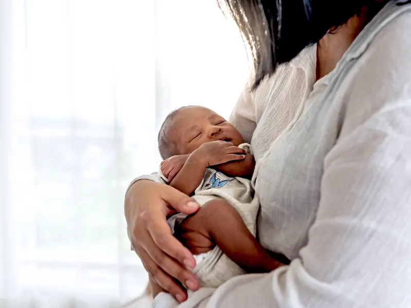 Woman experiencing postpartum depression gently holding her newborn in her arms