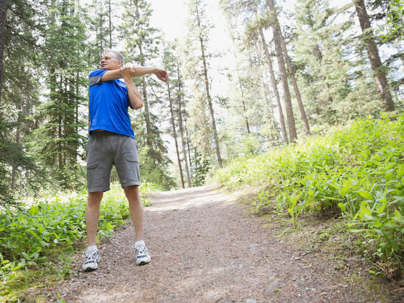 man stretching in the woods on a hiking trail