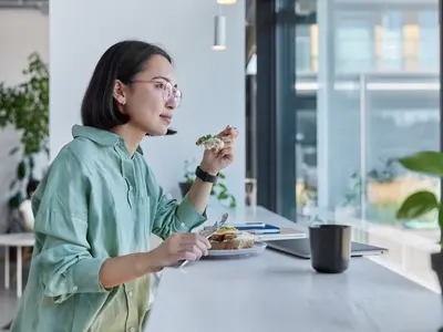 Una mujer se sienta a disfrutar de su almuerzo después de aprender los signos de comer por estrés y cómo manejarlo