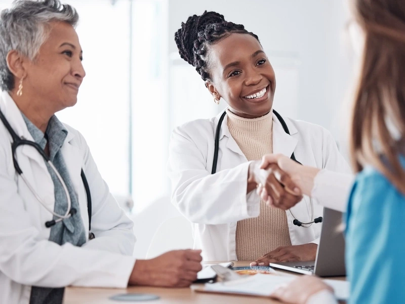 Medical providers smiling and shaking hands during an interview.