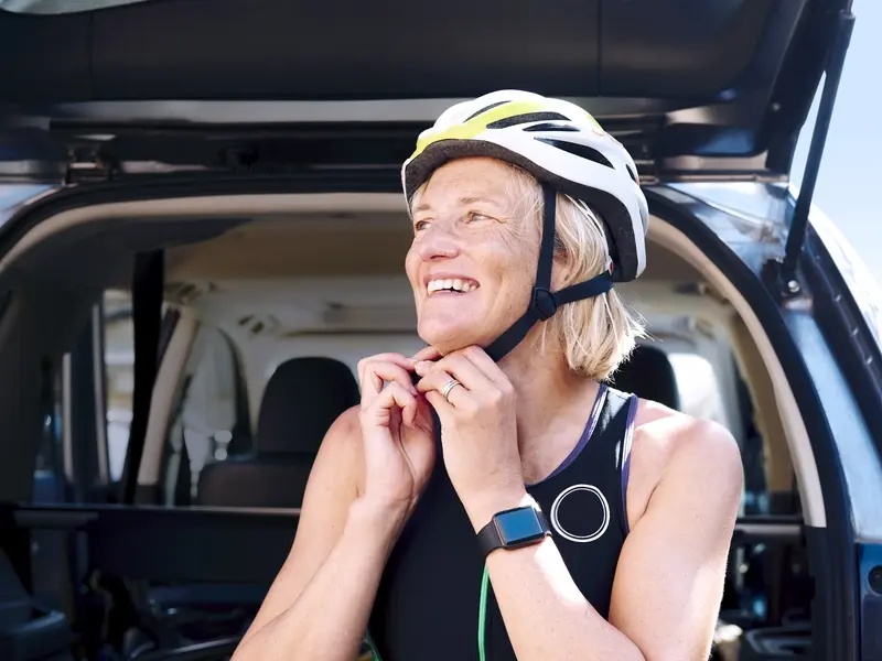 A woman smiles as she puts on a cycling helmet