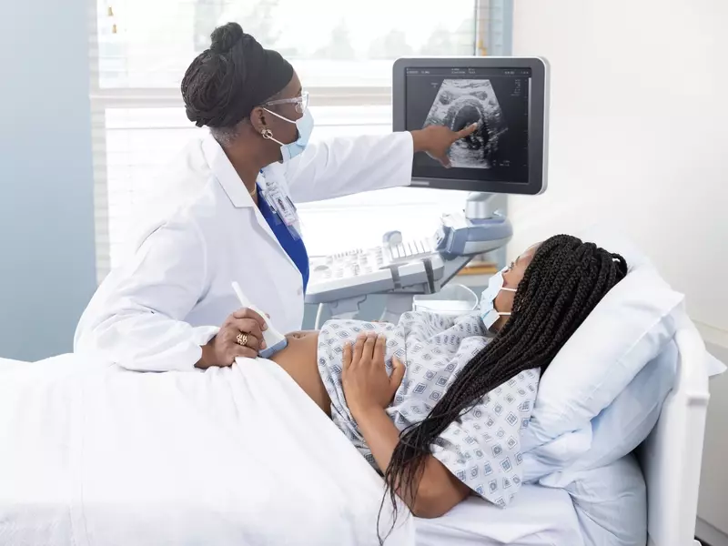 Pregnant woman receiving maternity care and sonogram from medical provider in a doctor's office setting