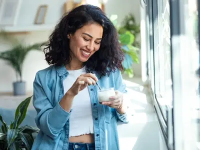 A woman enjoying a healthy meal after learning what to eat on your period to feel your best. 