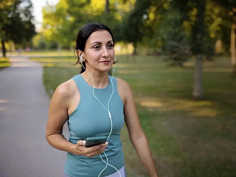 Woman listening to music while walking in a park after receiving spinal decompression treatment