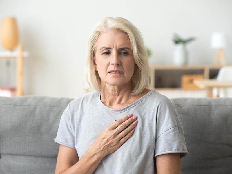 patient feeling the symptoms of Heart valve disease with her hand over her heart