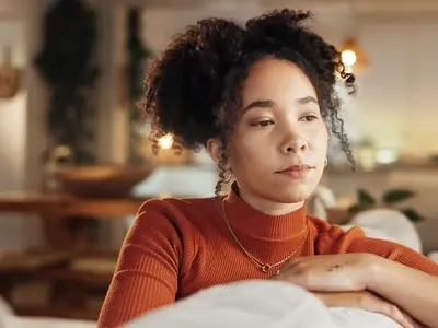 A woman sits on the sofa experiencing fatigue, a common sign of thyroid problems 