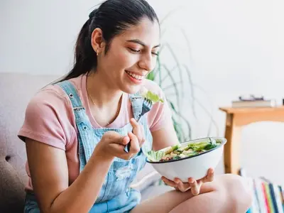 A woman standing eating foods that help balance hormones.