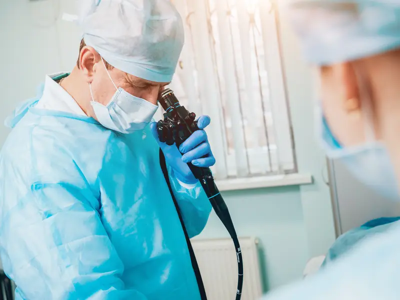 doctor in scrubs performing a colonoscopy on a patient