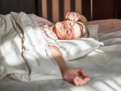 A woman waking up after a restful night sleep, showing menopause and sleep improvements.