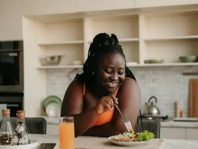 A woman standing in her kitchen eating healthy food, one of the natural remedies for acid reflux.