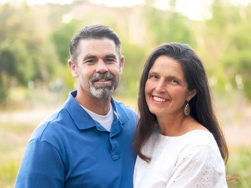 man and woman smiling at camera outside on a sunny day