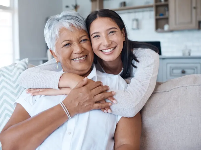 A mother and daughter pose for a picture on the couch in their living room