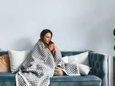 Una mujer se sienta en un sofá preguntándose cuánto tiempo es contagiosa la gripe