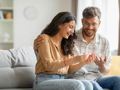 A woman and her partner sitting on a couch learning they are pregnant and wanting to know what things to do in the early stages of pregnancy.