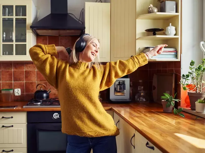 Woman dancing joyfully while listening to music through headphones, celebrating a positive OBGYN visit