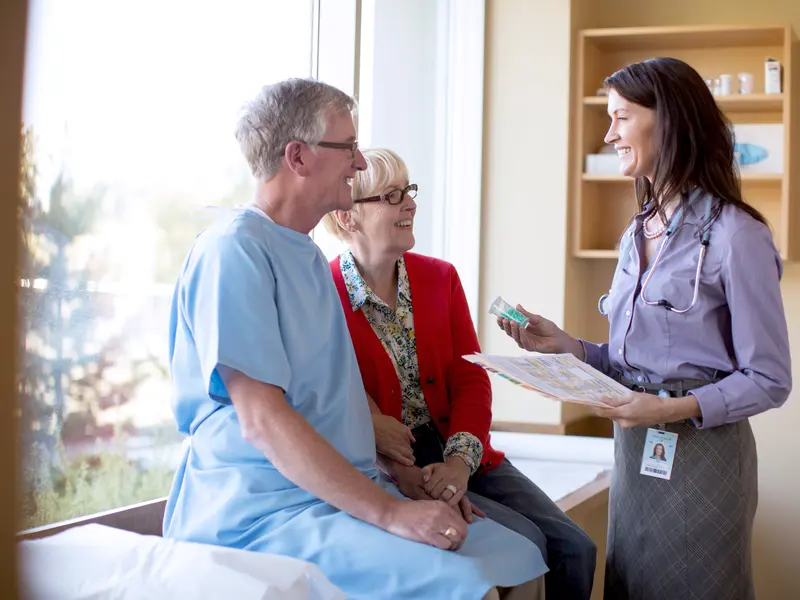 Female medical provider explaining the procedure and benefits of a thoracotomy to a male patient, with his wife sitting beside him
