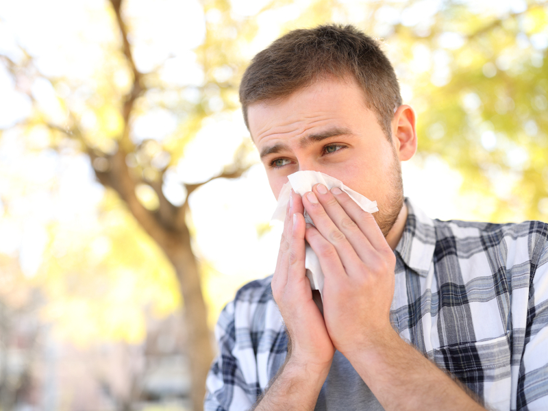 man suffering from measles sneezing into a tissue