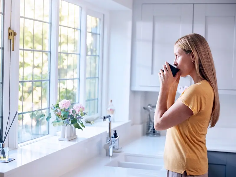 Patient suffering from vaginitis drinking coffee in her kitchen