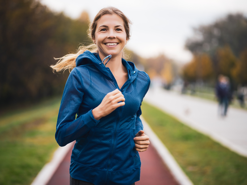 woman exercising her hips by running outside on a track