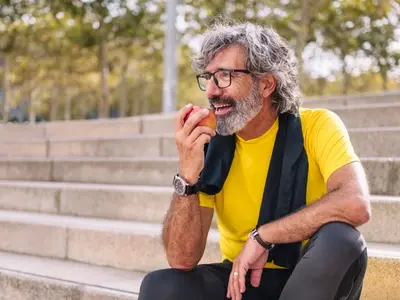 A man eating an apple living with colitis and symptoms of colitis