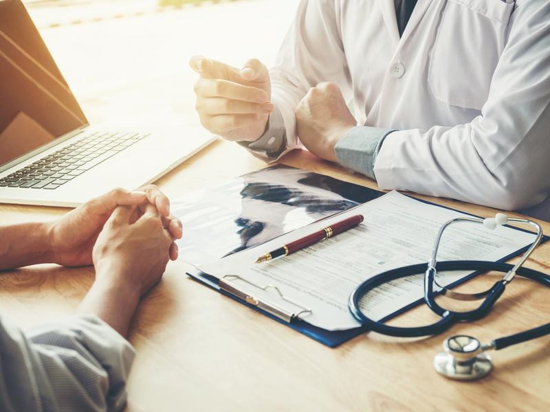 Cardiologist sitting at a desk with a patient, explaining follow-up care for a ventricular assist device (VAD)