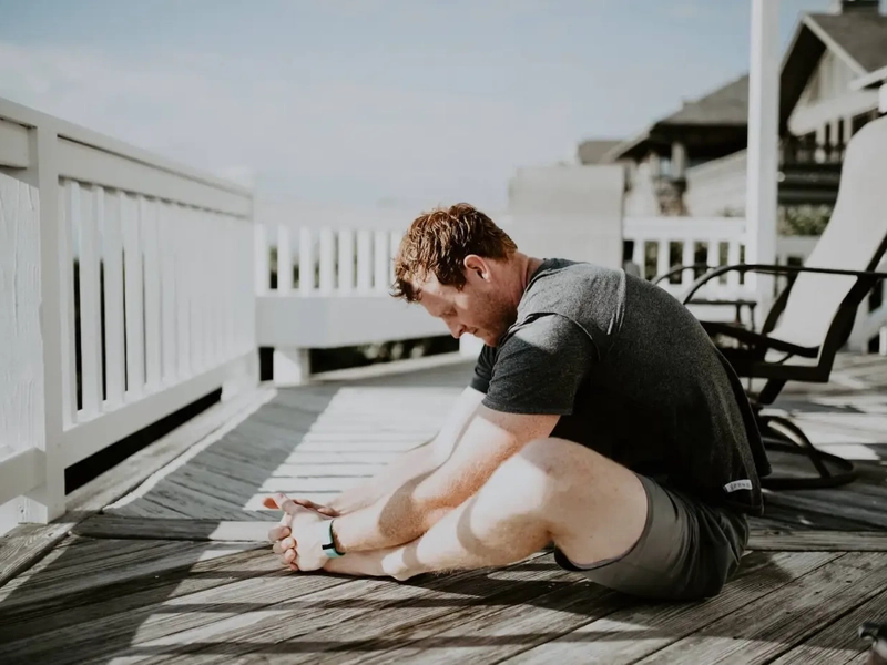 man dealing thoracic outlet syndrome on a porch deck stretching