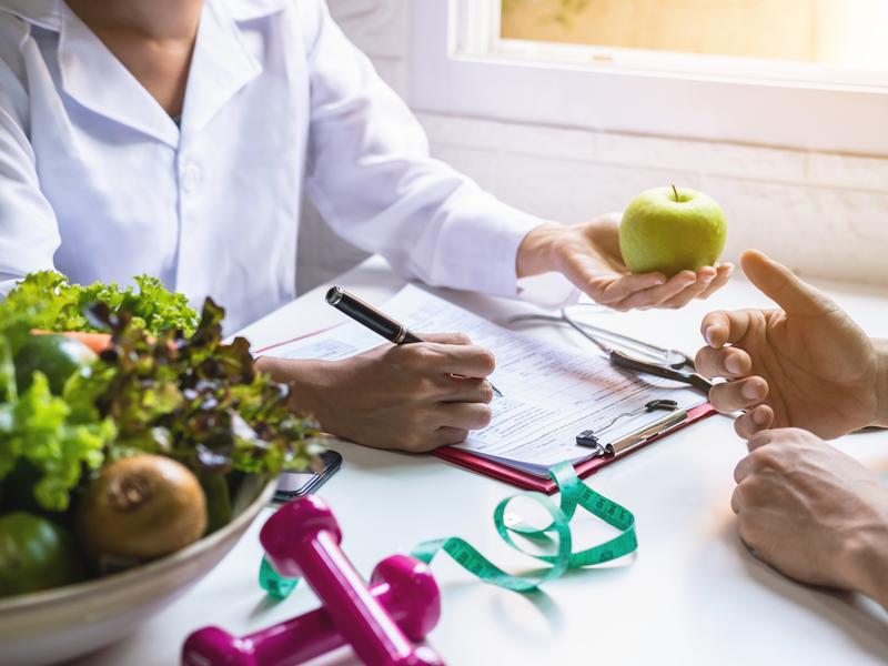 Cardiologist sitting at a desk with a patient, discussing the benefits and expectations of cardiac rehabilitation