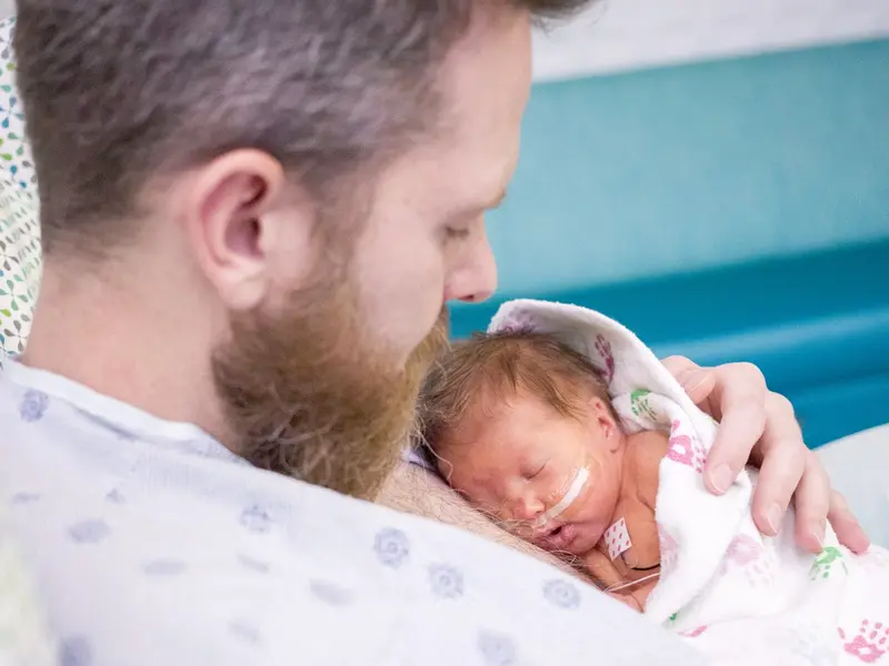 Dad holding newborn baby in NICU