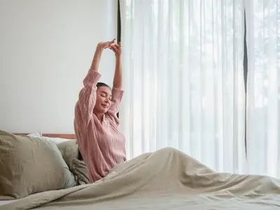 A woman wakes up in bed after learning proper sleep hygiene to get a good night’s sleep