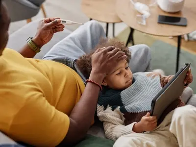 A mother sits on a couch with her young child with whooping cough and pertussis symptoms