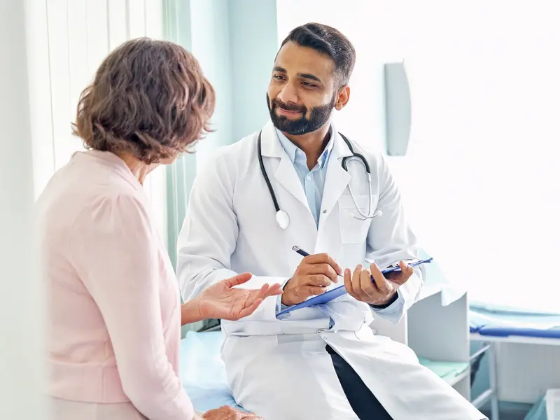 Vascular surgeon smiling and reviewing the patient's medical records while explaining the risks and benefits of vascular surgery