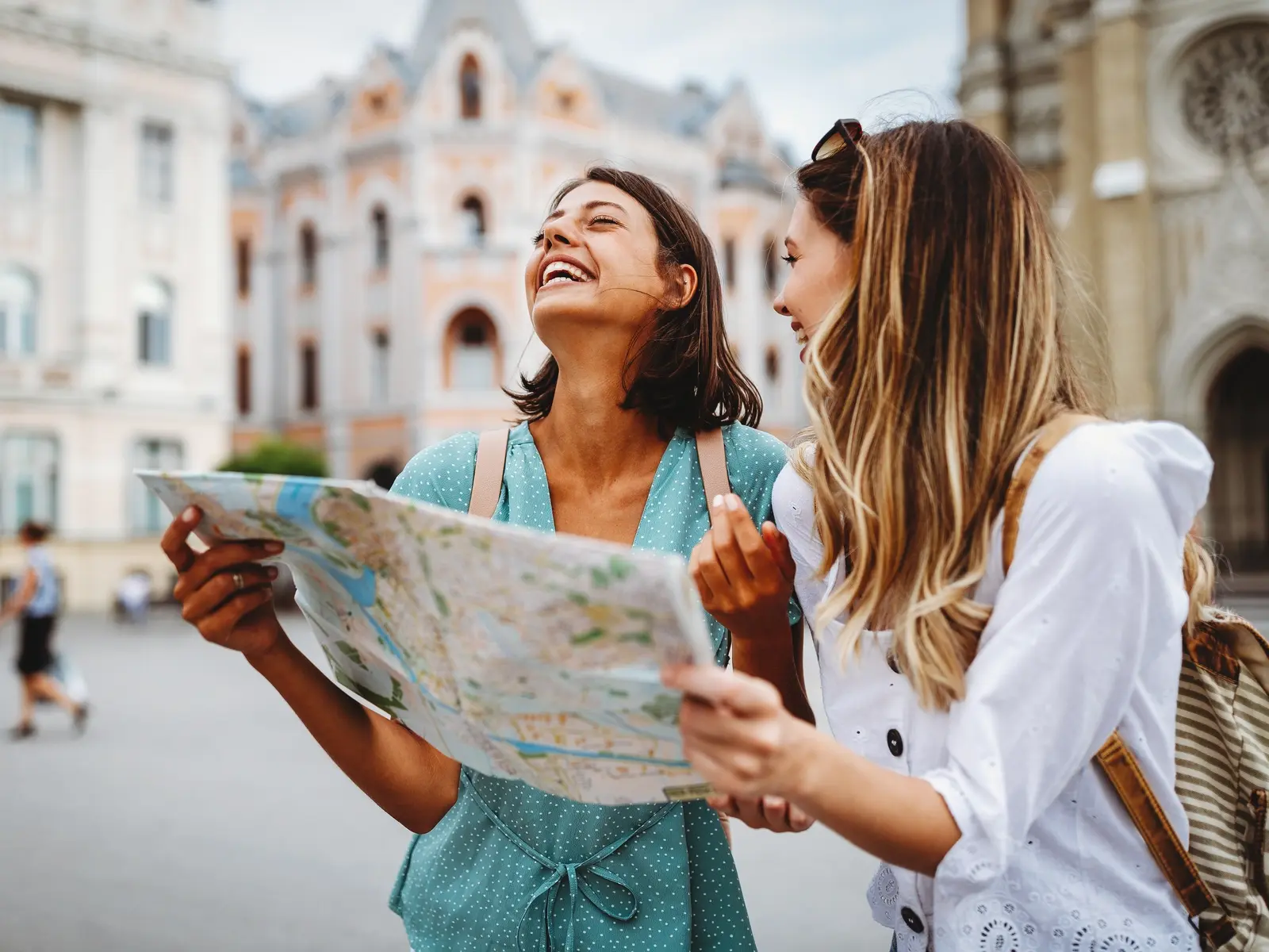 Two girls traveling looking at a map and smiling