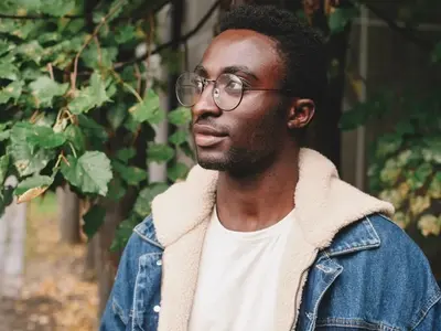 Un joven con gafas de pie, destacándose después de aprender la diferencia entre la depresión clínica y la depresión