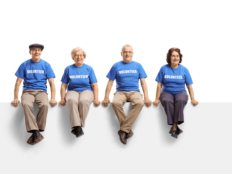 Four elderly aged volunteers smiling while sitting next to each other