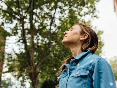 Una mujer está al aire libre en Texas experimentando síntomas de fiebre del cedro