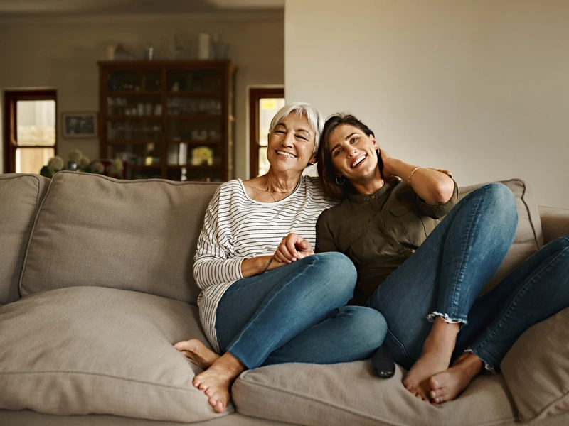 Mother and daughter sitting happily on a couch discussing menorrhagia