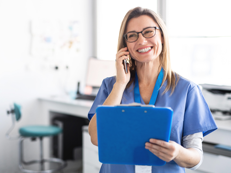 A healthcare provider smiling as she reviews notes during a virtual care visit