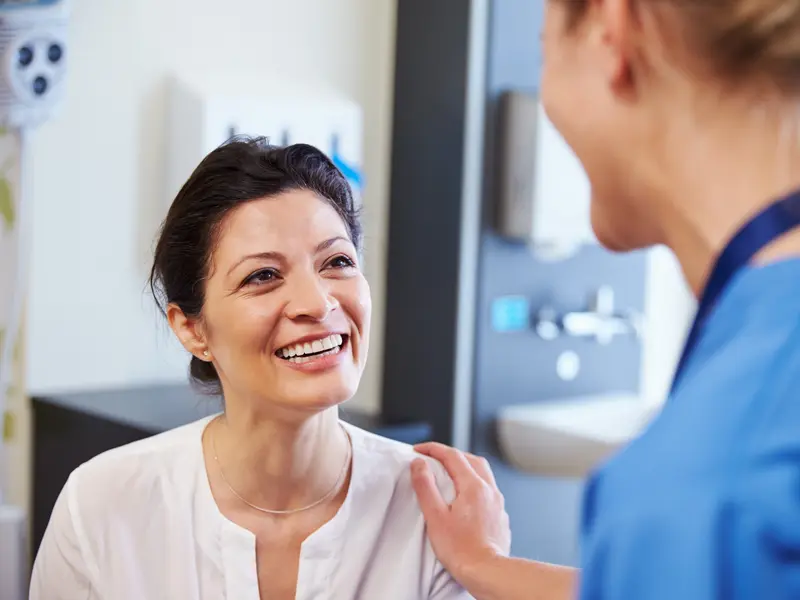 Female medical physician offering reassurance with a comforting hand on a female patient, explaining Video-assisted Thoracoscopic Surgery (VATS) as the patient smiles