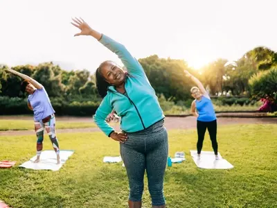 Three women stretching on yoga mats in the park while taking GLP-1 for weight loss