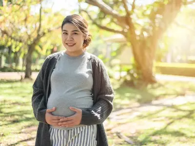 A woman during pregnancy experiencing sciatic nerve pain while outside walking. 