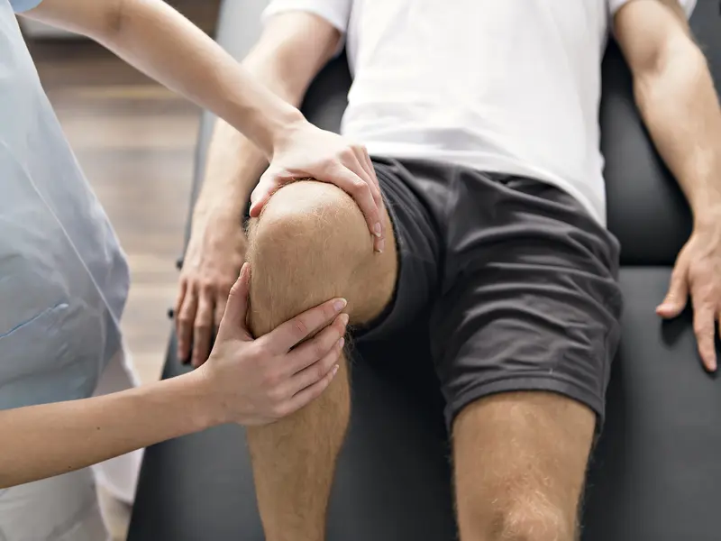 medical provider examining man's knee for torn meniscus