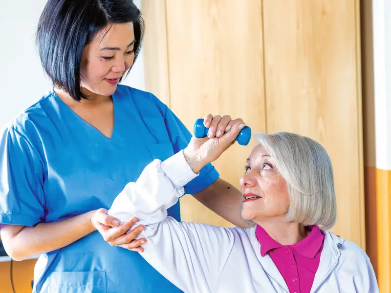 female physical therapist working with a woman stroke patient inside of hospital setting