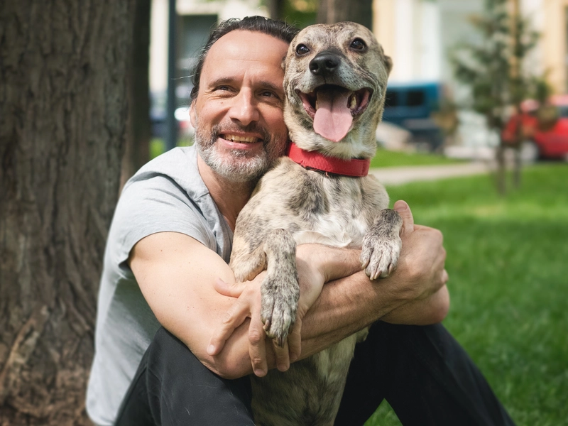 colonoscopy patient sitting in a park with his dog